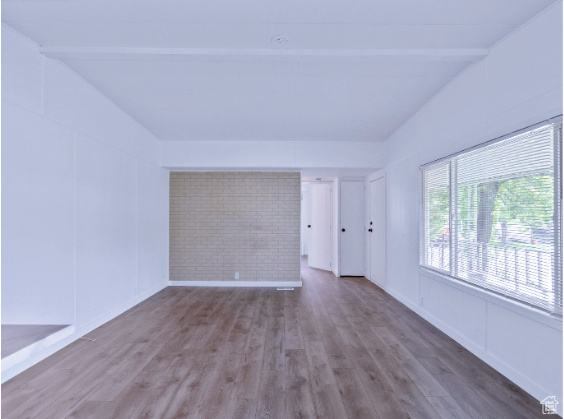 Unfurnished room featuring vaulted ceiling with beams and hardwood / wood-style flooring