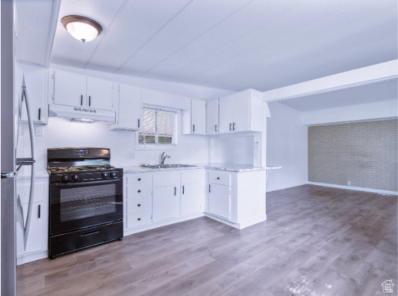 Kitchen with gas stove, white cabinets, sink, hardwood / wood-style floors, and stainless steel fridge
