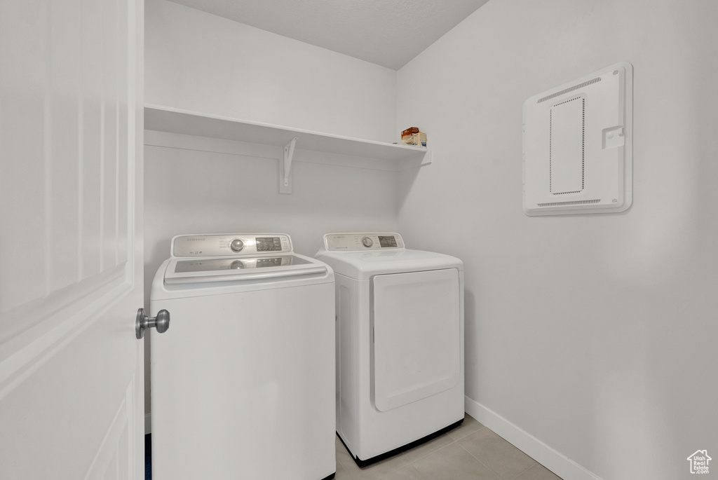 Washroom featuring washing machine and dryer and light tile floors