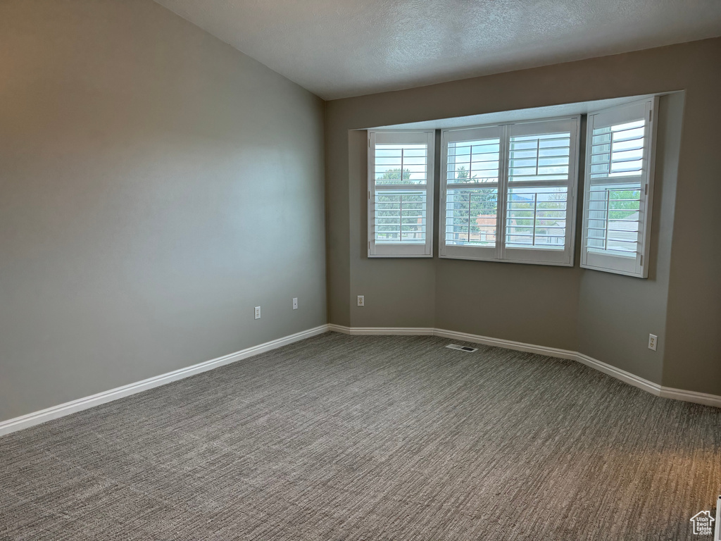 Empty room with a textured ceiling and carpet flooring