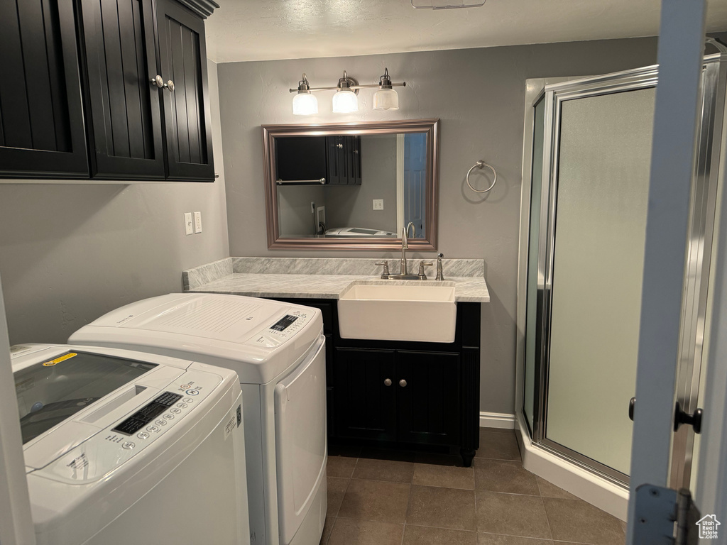 Clothes washing area featuring dark tile flooring, sink, and washer and dryer