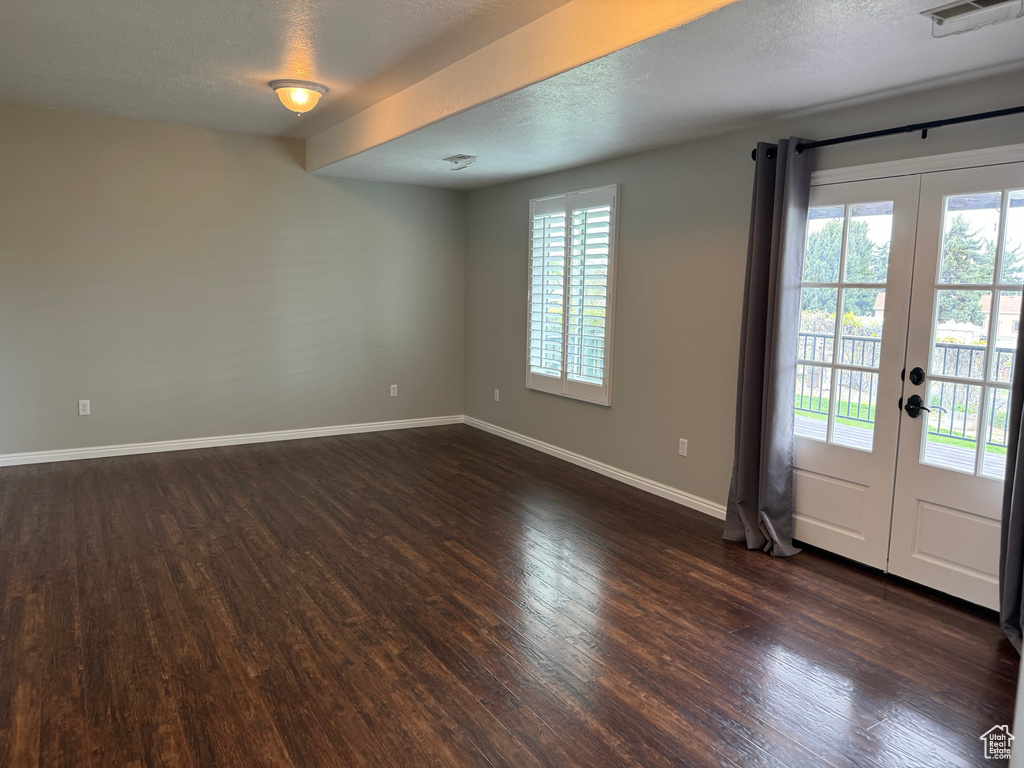 Empty room with french doors, dark hardwood / wood-style floors, and a textured ceiling