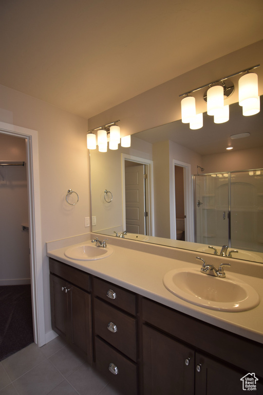 Bathroom featuring dual sinks, oversized vanity, tile flooring, and walk in shower