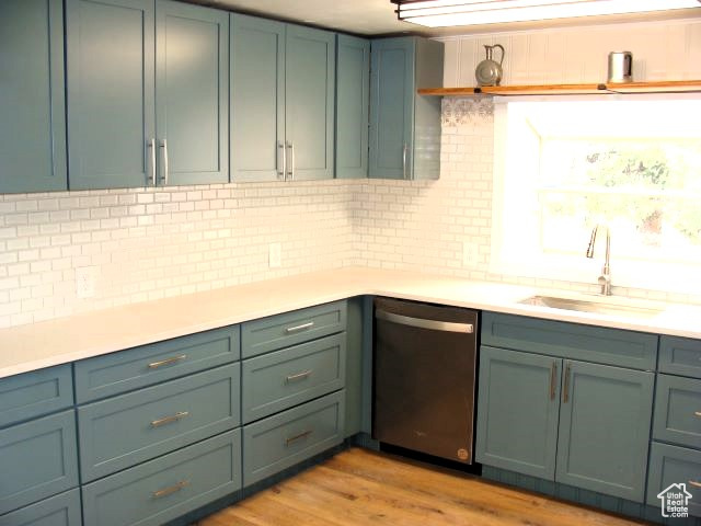 Kitchen featuring light hardwood / wood-style flooring, green cabinetry, tasteful backsplash, sink, and stainless steel dishwasher