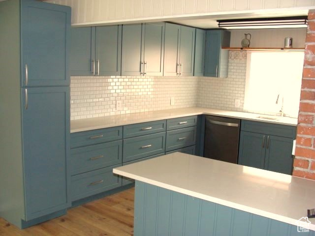 Kitchen featuring backsplash, sink, hardwood / wood-style flooring, and stainless steel dishwasher
