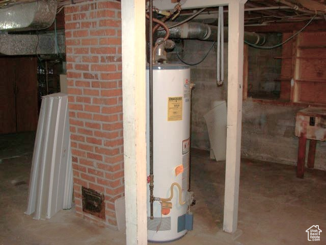 Basement with water heater and brick wall