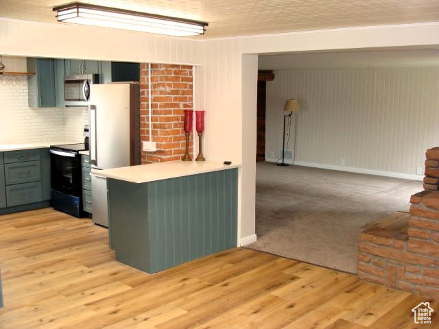 Kitchen with black electric range, light hardwood / wood-style floors, backsplash, refrigerator, and green cabinets
