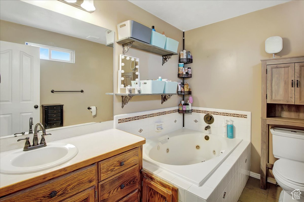 Bathroom featuring vanity with extensive cabinet space, toilet, and tile flooring