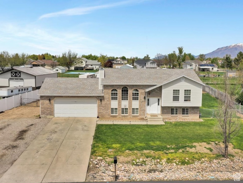 View of front of property with a mountain view, a front lawn, and a garage