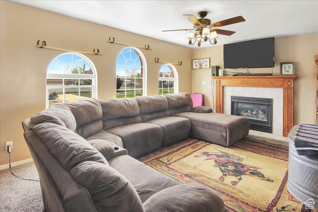 Carpeted living room featuring plenty of natural light, ceiling fan, and a tiled fireplace