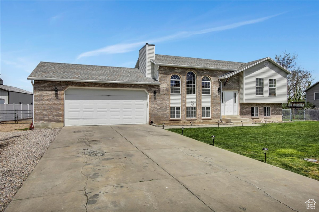 Split foyer home featuring a garage and a front lawn