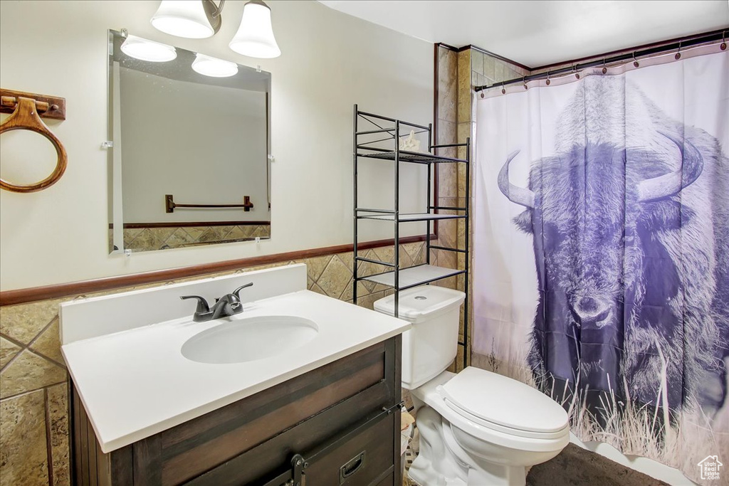 Bathroom with tile walls, toilet, and large vanity