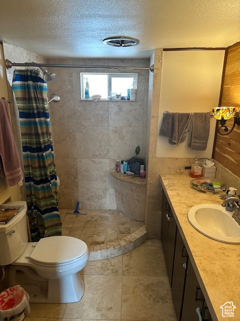 Bathroom featuring vanity, toilet, a shower with shower curtain, and a textured ceiling