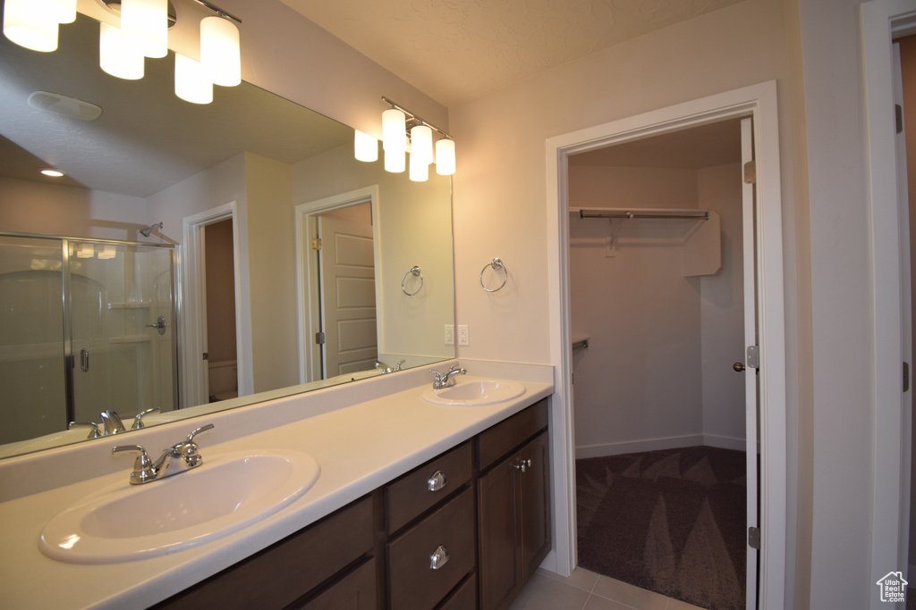 Bathroom featuring walk in shower, toilet, tile floors, and dual vanity