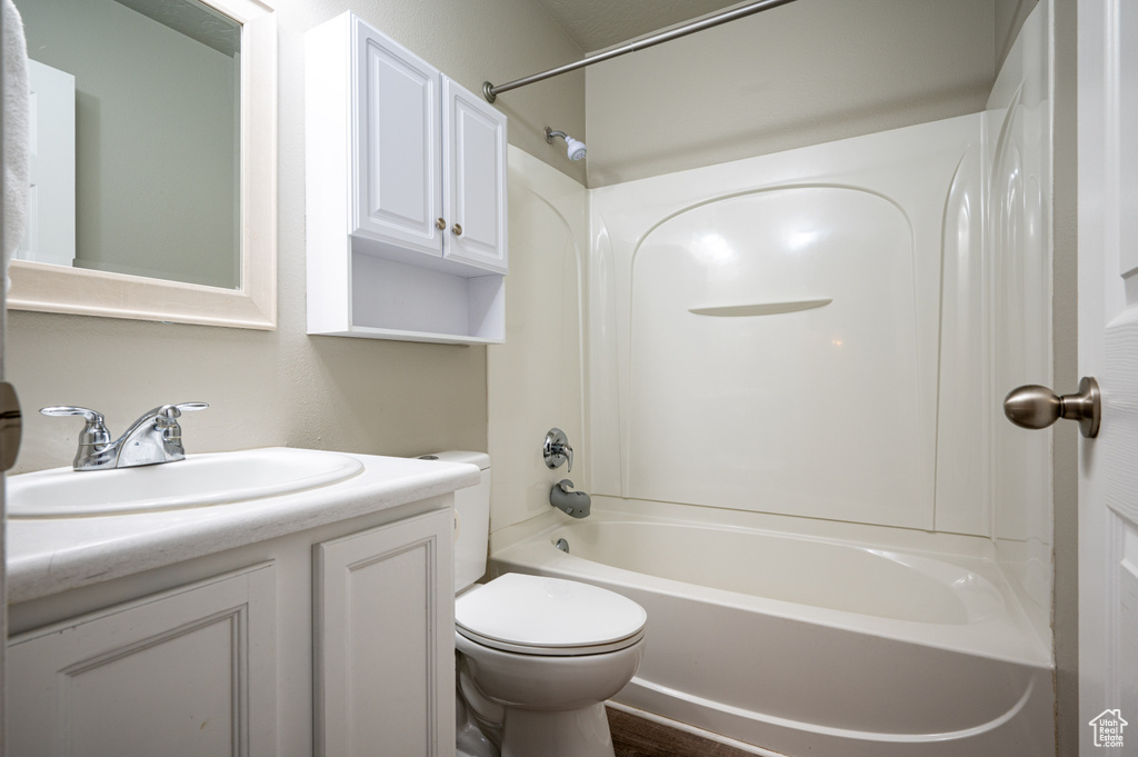Full bathroom featuring hardwood / wood-style floors, shower / bathtub combination, vanity, and toilet