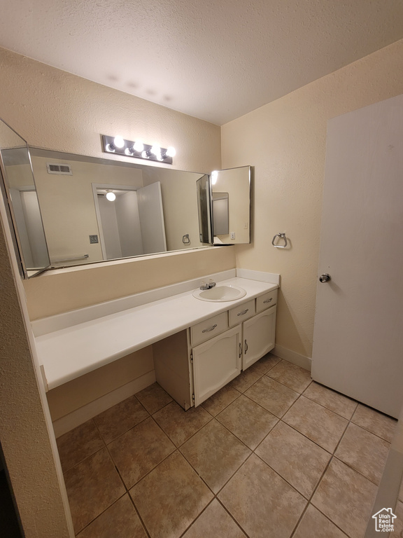 Bathroom featuring oversized vanity, a textured ceiling, and tile flooring