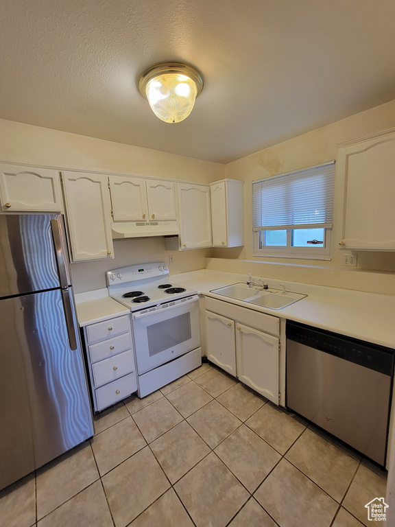 Kitchen with white cabinets, sink, stainless steel appliances, and light tile floors