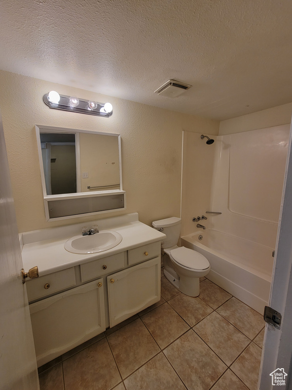 Full bathroom featuring large vanity, tile flooring, toilet, washtub / shower combination, and a textured ceiling