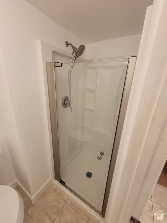 Bathroom featuring tile flooring, walk in shower, and toilet