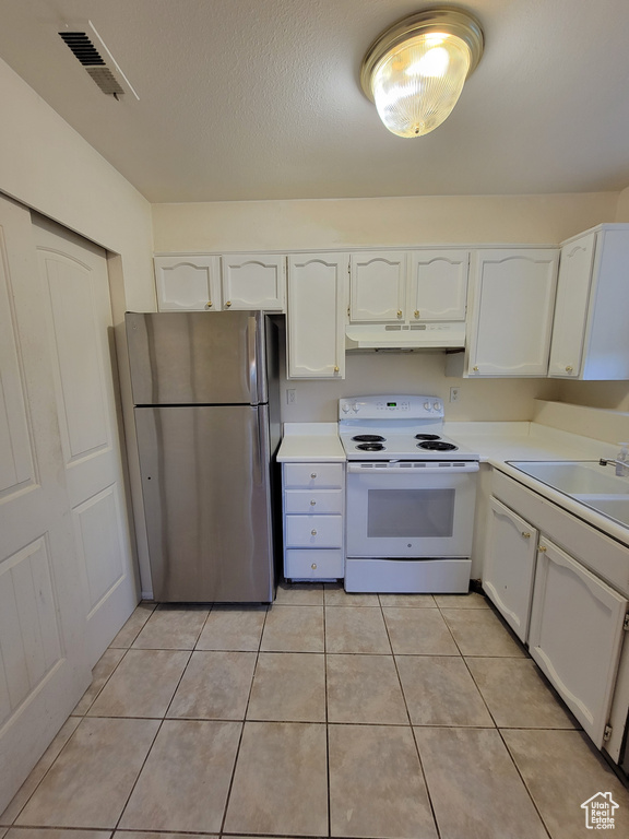 Kitchen with white cabinetry, white range with electric stovetop, stainless steel fridge, and light tile flooring
