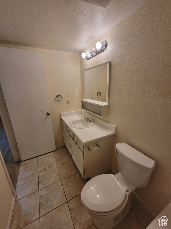 Bathroom featuring toilet, tile flooring, vanity, and a textured ceiling