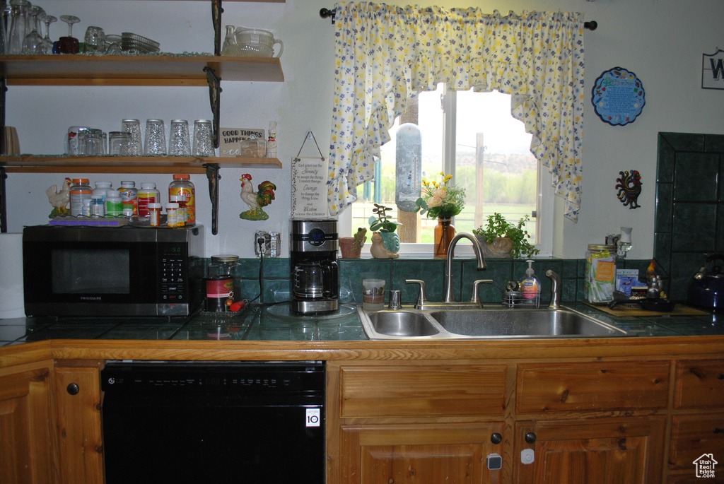 Kitchen featuring sink, black dishwasher, tasteful backsplash, and tile countertops