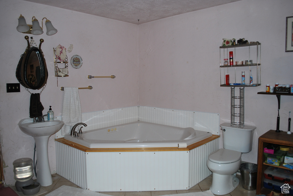 Bathroom featuring tile flooring, toilet, a textured ceiling, and a bathing tub