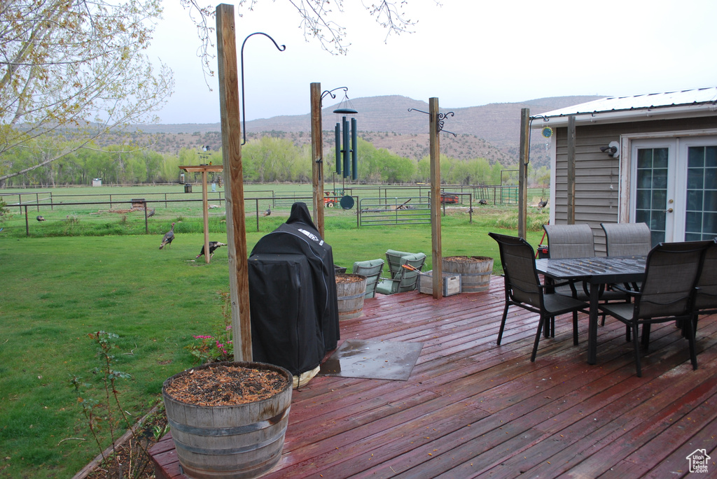 Wooden deck featuring a mountain view and a yard