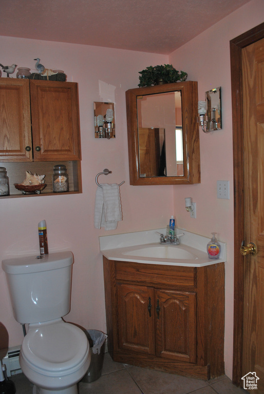 Bathroom with a baseboard heating unit, tile flooring, toilet, and vanity