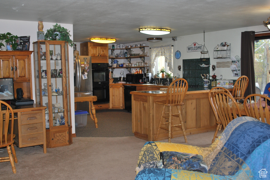 Kitchen featuring sink, light carpet, and black appliances