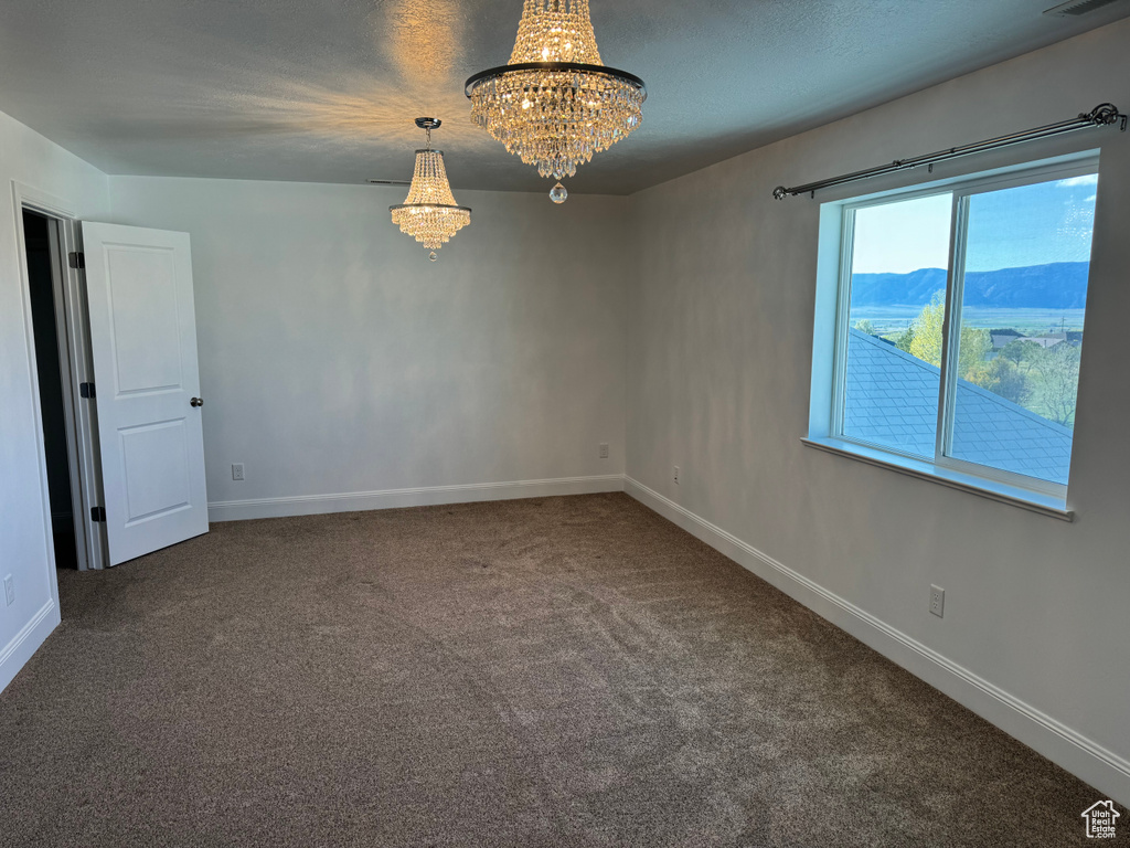 Carpeted empty room with a mountain view and a notable chandelier