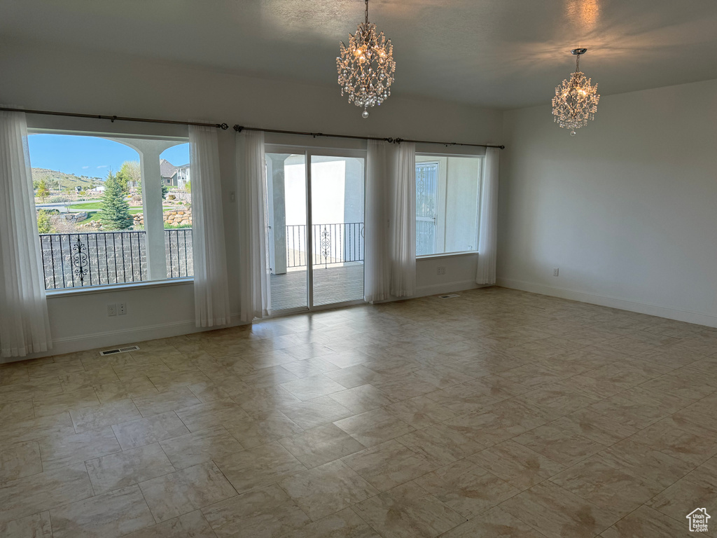 Empty room with tile flooring and an inviting chandelier