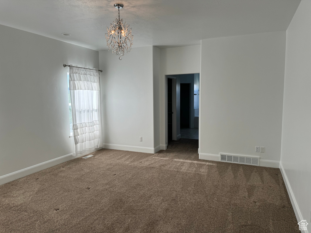 Spare room featuring carpet and an inviting chandelier