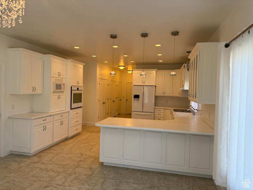 Kitchen with white appliances, pendant lighting, kitchen peninsula, and light tile floors