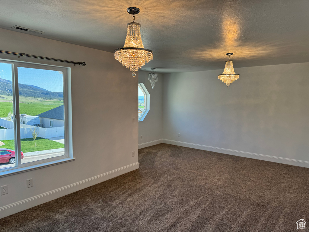 Empty room featuring a mountain view, carpet floors, and a notable chandelier