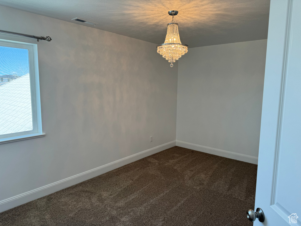 Carpeted empty room with an inviting chandelier