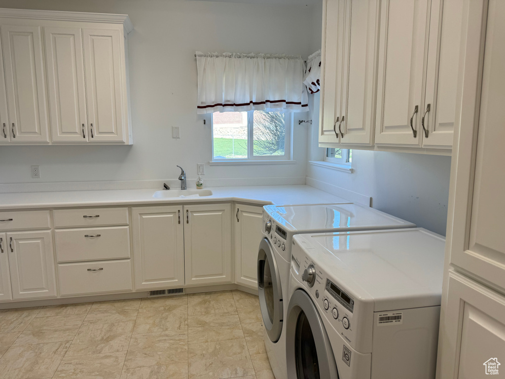Laundry room with cabinets, sink, light tile floors, and washer and dryer