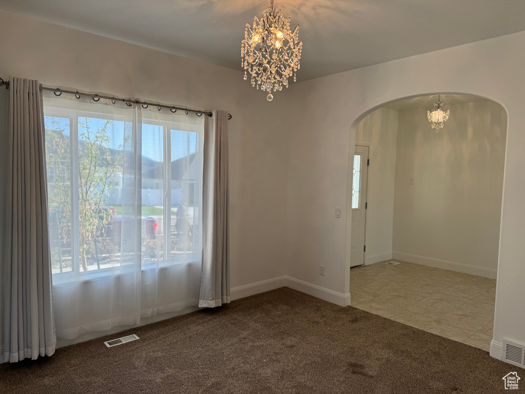 Spare room with a chandelier and tile flooring