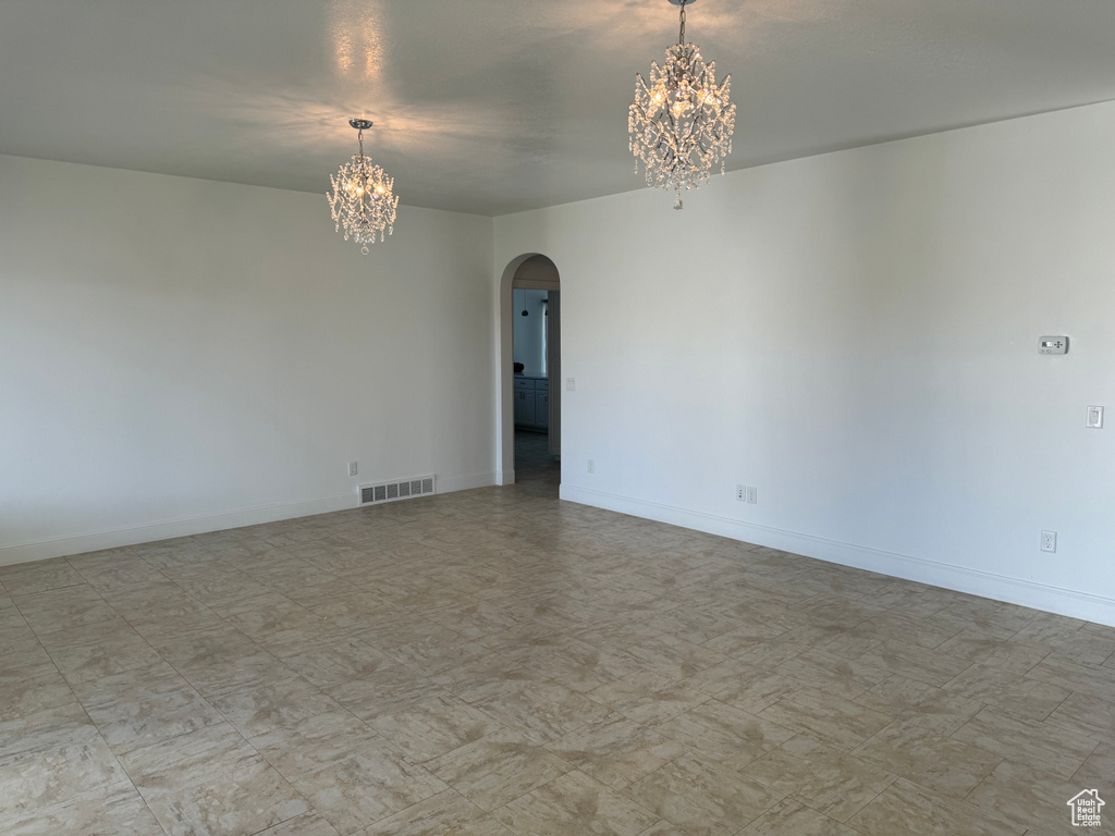 Empty room with an inviting chandelier and light tile flooring