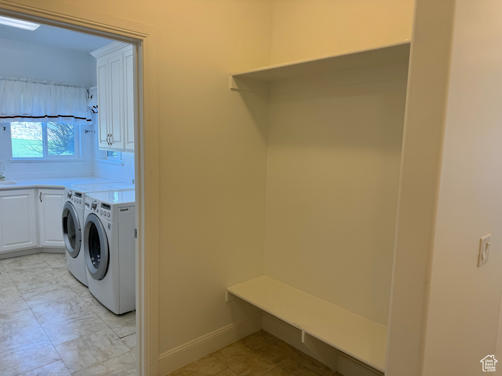 Laundry area featuring cabinets, independent washer and dryer, light tile floors, and sink