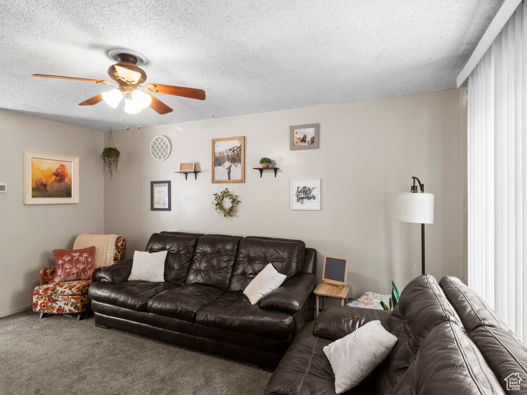 Living room featuring ceiling fan, carpet, and a textured ceiling
