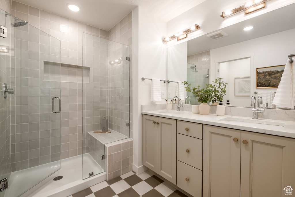 Bathroom with a shower with door, dual bowl vanity, and tile flooring