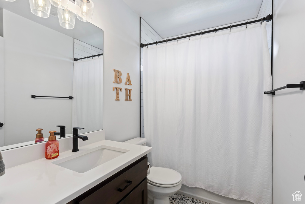 Bathroom with a chandelier, vanity, and toilet