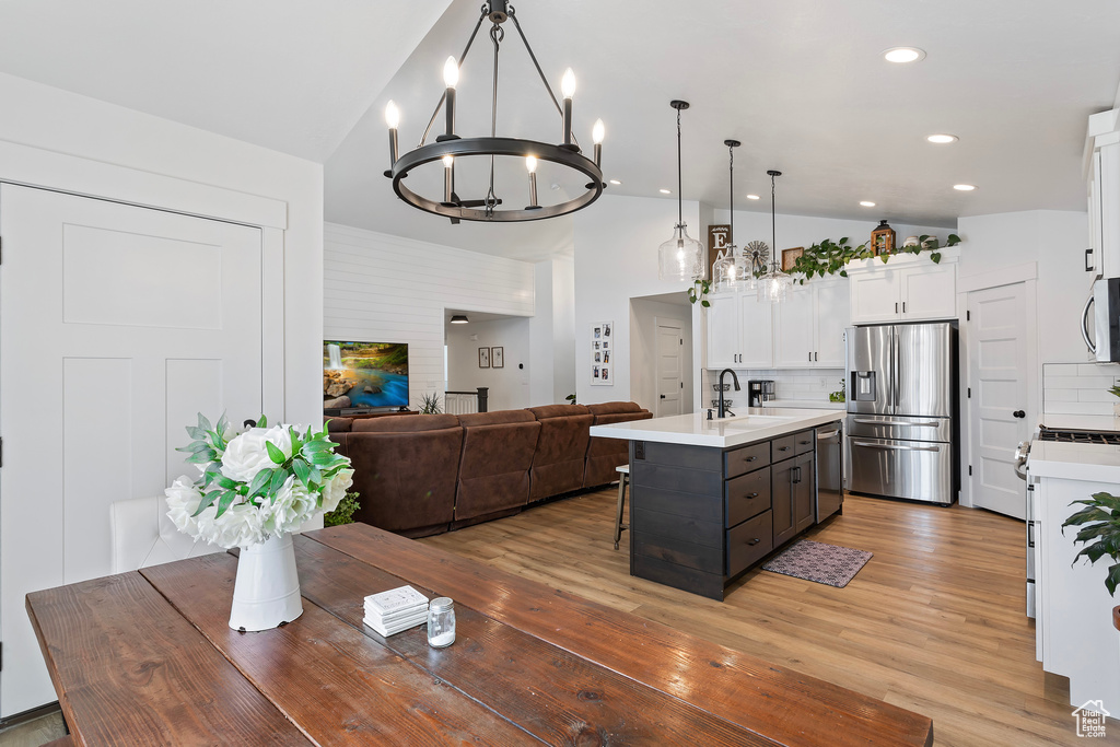 Kitchen with white cabinets, light hardwood / wood-style flooring, tasteful backsplash, and stainless steel appliances