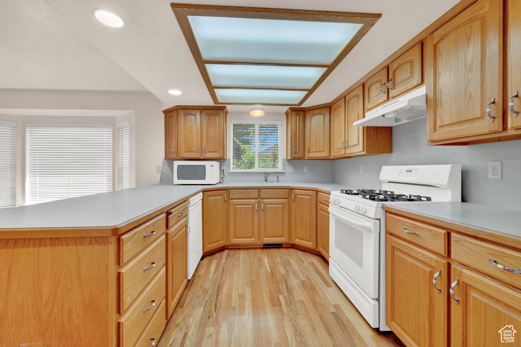 Kitchen with kitchen peninsula, light hardwood / wood-style flooring, white appliances, and sink