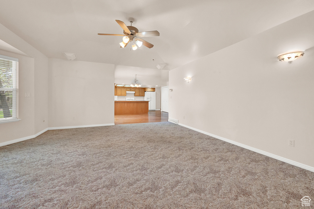 Unfurnished living room featuring ceiling fan, carpet floors, and vaulted ceiling