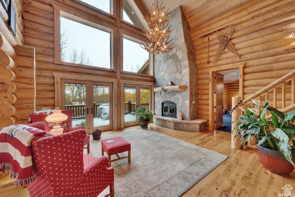 Living room featuring french doors, wood-type flooring, log walls, and high vaulted ceiling