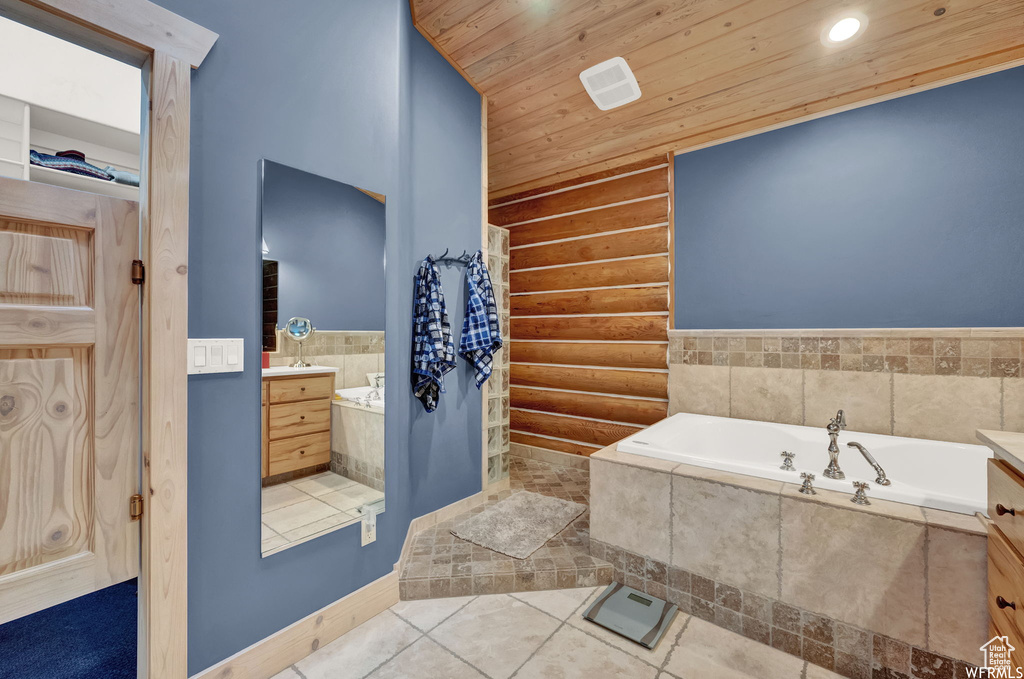 Bathroom with log walls, tiled tub, vanity, and tile floors