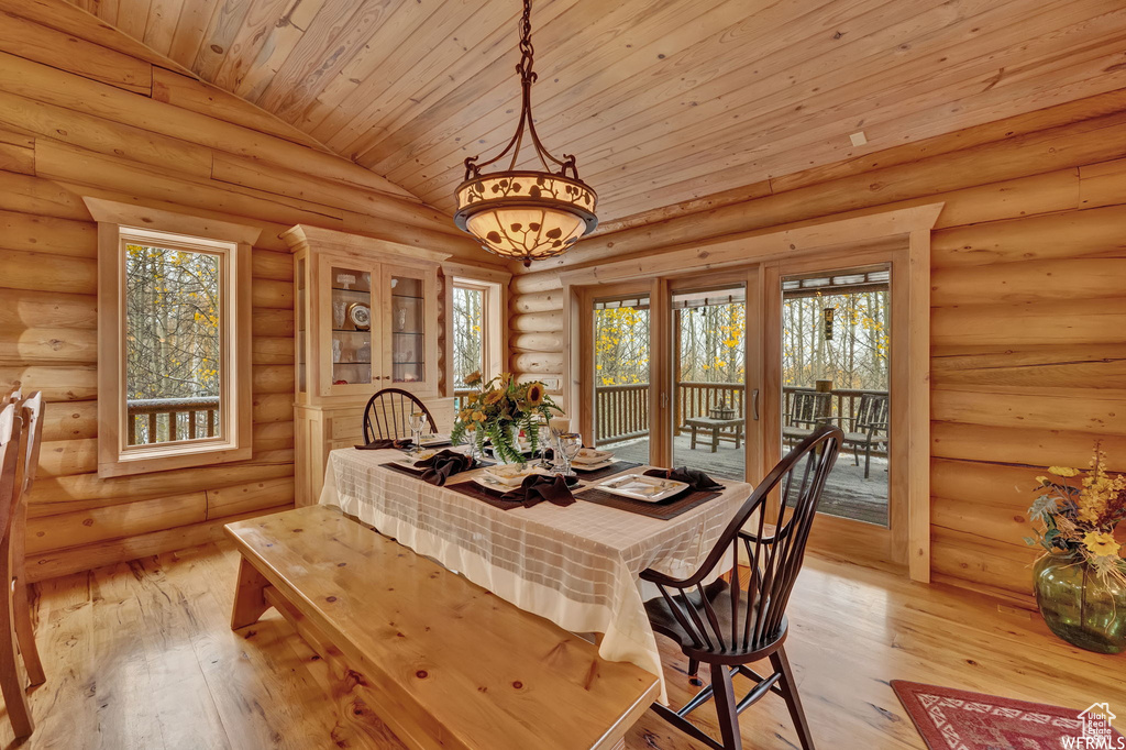 Dining space featuring light hardwood / wood-style floors, log walls, wooden ceiling, and lofted ceiling
