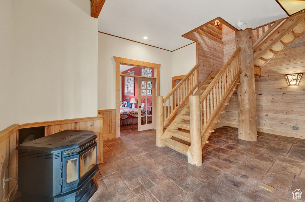 Staircase with wooden walls, a wood stove, and dark tile flooring